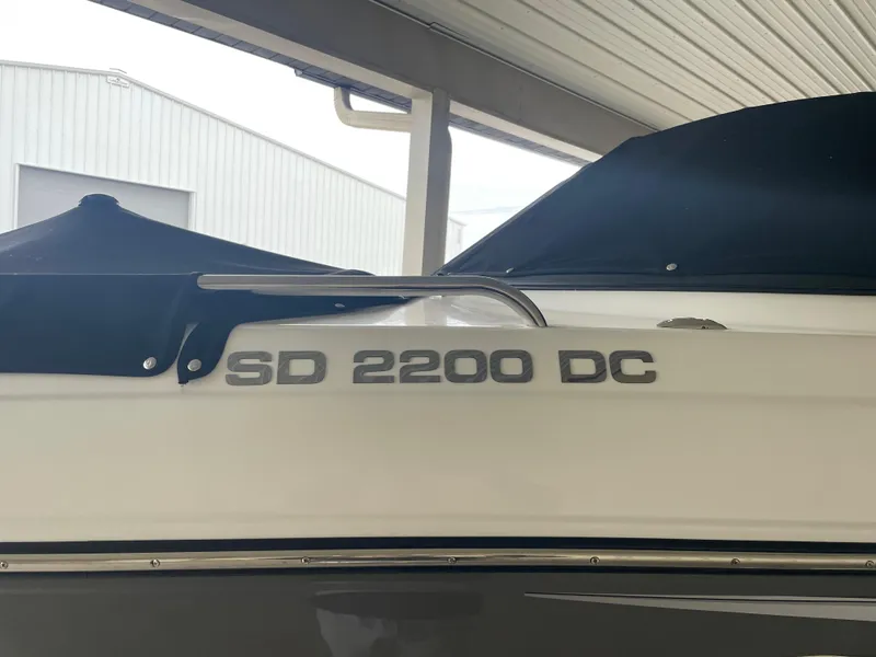 Slide: The Image of 2022 Hurricane SunDeck 2200 DC OB boat under a covered dock. - 2