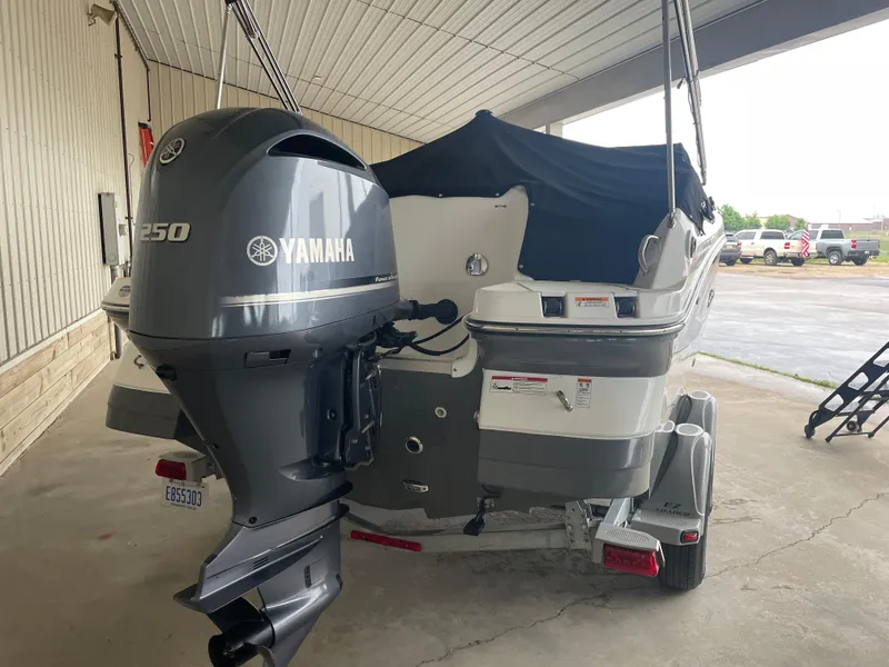 Slide: The Image of 2022 Hurricane SunDeck 2200 DC OB boat with Yamaha engine, parked under a shelter. - 4