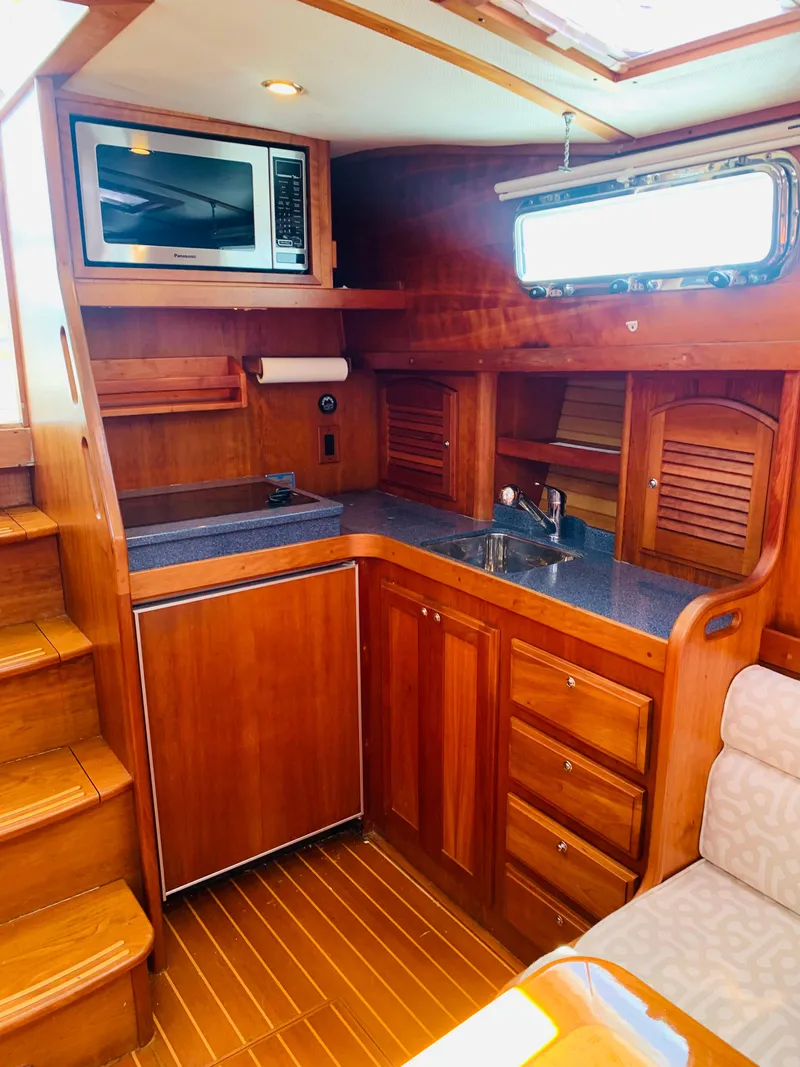 Slide: The Image of 2004 Sabre 42 Hardtop Express galley with wood cabinetry, sink, microwave, and compact fridge. - 13