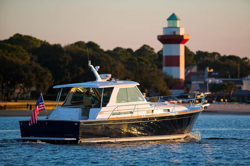 Slide: The Image of 2004 Sabre 42 Hardtop Express yacht cruising near a lighthouse at sunset. - 39