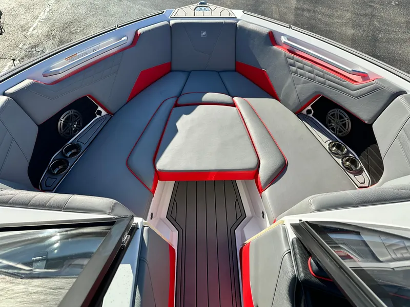 Slide: The Image of 2022 Nautique S23 boat interior with gray and red seating, cup holders, and speakers. - 10