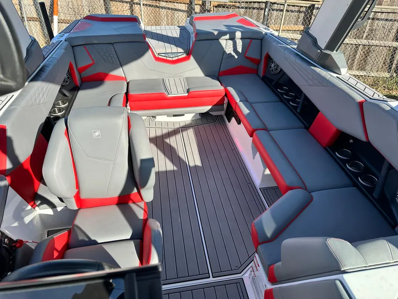 Slide: The Image of 2022 Nautique S23 boat interior with gray and red seating, cup holders, and spacious layout. - 11