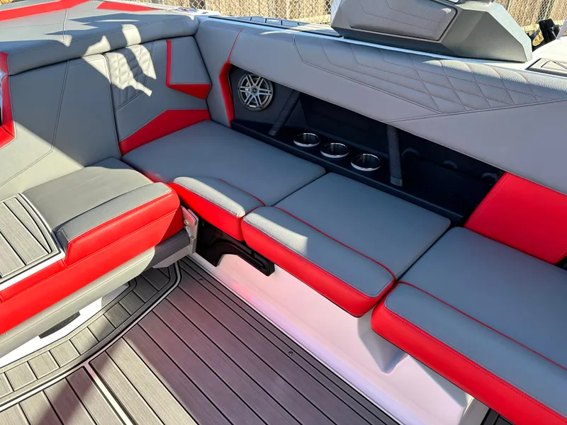 Slide: The Image of 2022 Nautique S23 boat interior with red and gray seating and cup holders. - 12