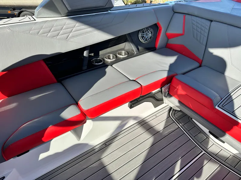 Slide: The Image of 2022 Nautique S23 boat interior with red and gray seating, cup holders, and speaker. - 13