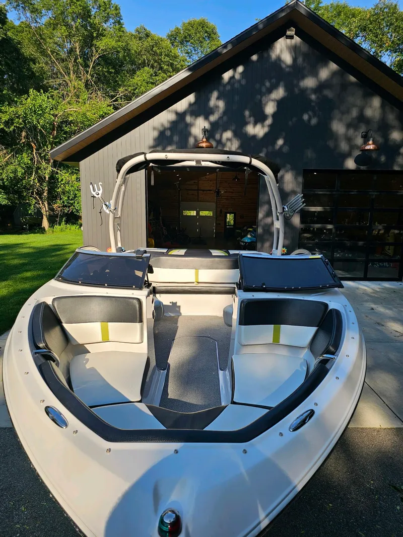 Slide: The Image of 2016 Four Winns H180 boat parked in front of a modern garage. - 2