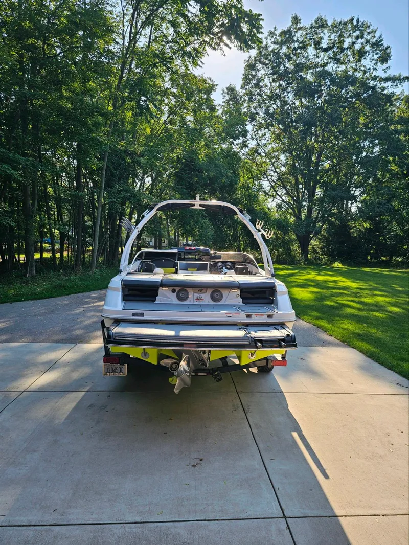Slide: The Image of 2016 Four Winns H180 boat on driveway, surrounded by lush green trees. - 3