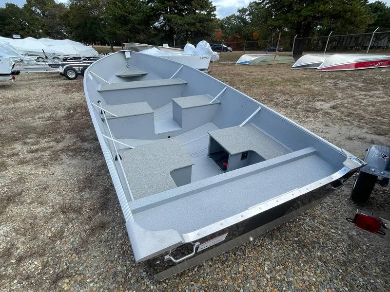 Slide: The Image of 2025 Lund SSV-16 Tiller boat, gray interior, parked on gravel lot. - 3