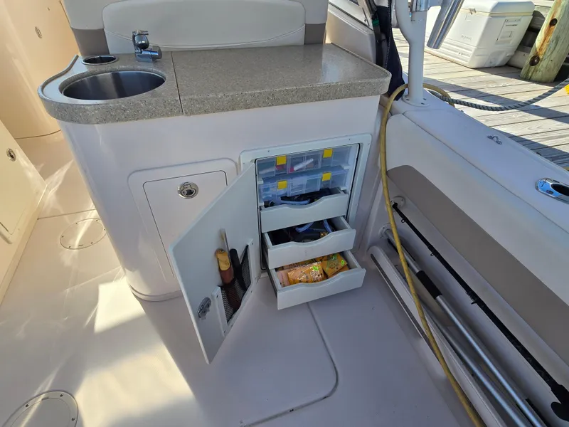 Slide: The Image of 2014 Grady-White Freedom 307 boat interior with open storage cabinet and sink. - 27