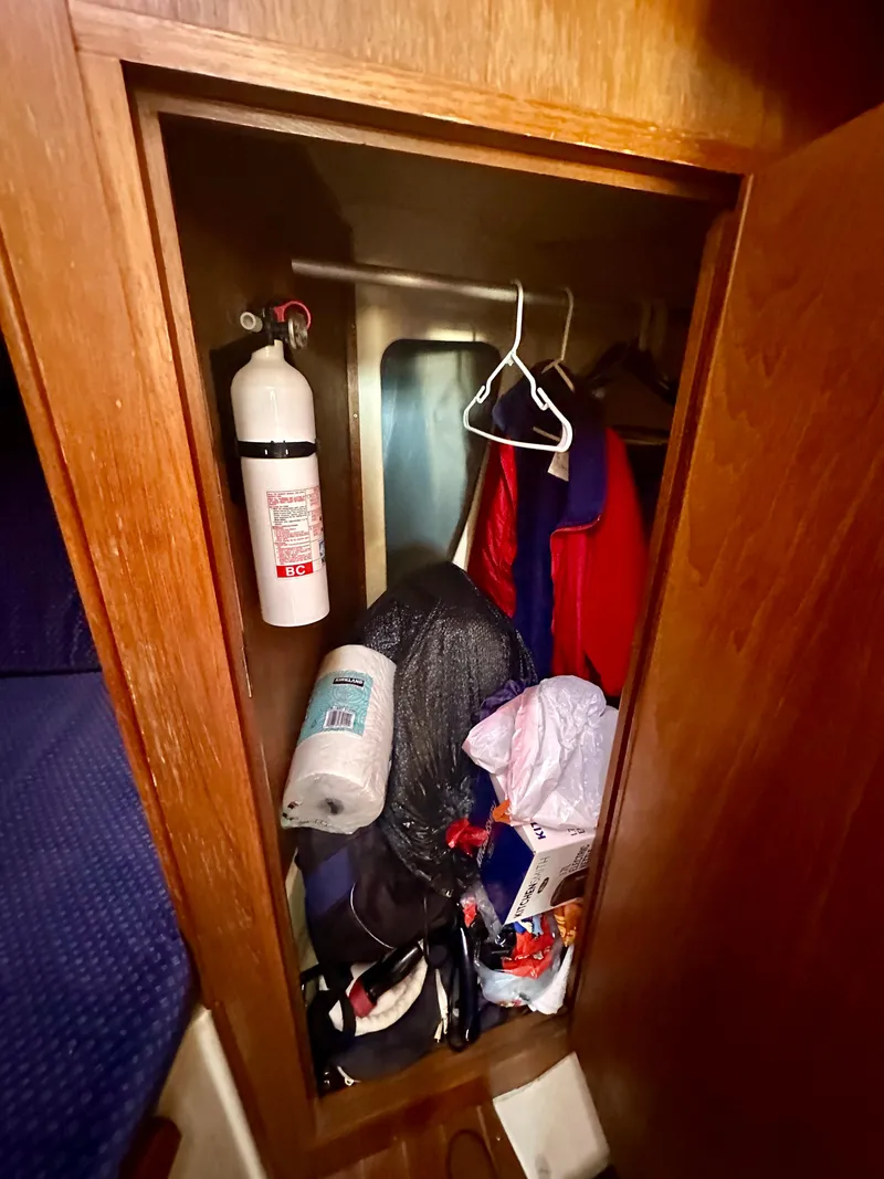 Slide: The Image of 1986 Nonsuch Ultra closet with fire extinguisher, clothes, and miscellaneous items. - 10