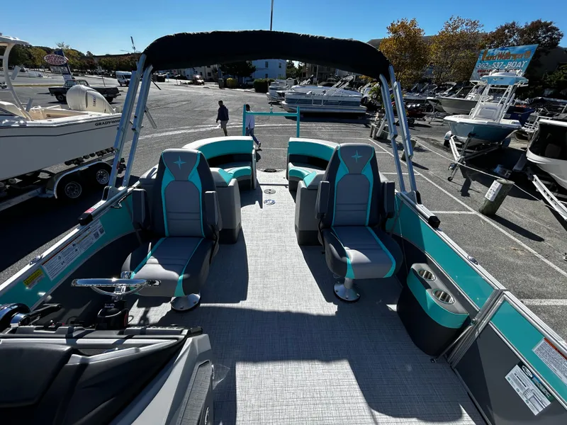 Slide: The Image of 2025 Berkshire 23RFX STS 3.0 pontoon boat with teal seating in a marina. - 17