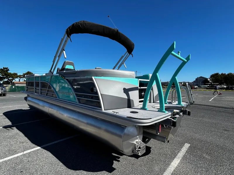 Slide: The Image of 2025 Berkshire 23RFX STS 3.0 pontoon boat in parking lot under clear blue sky. - 2