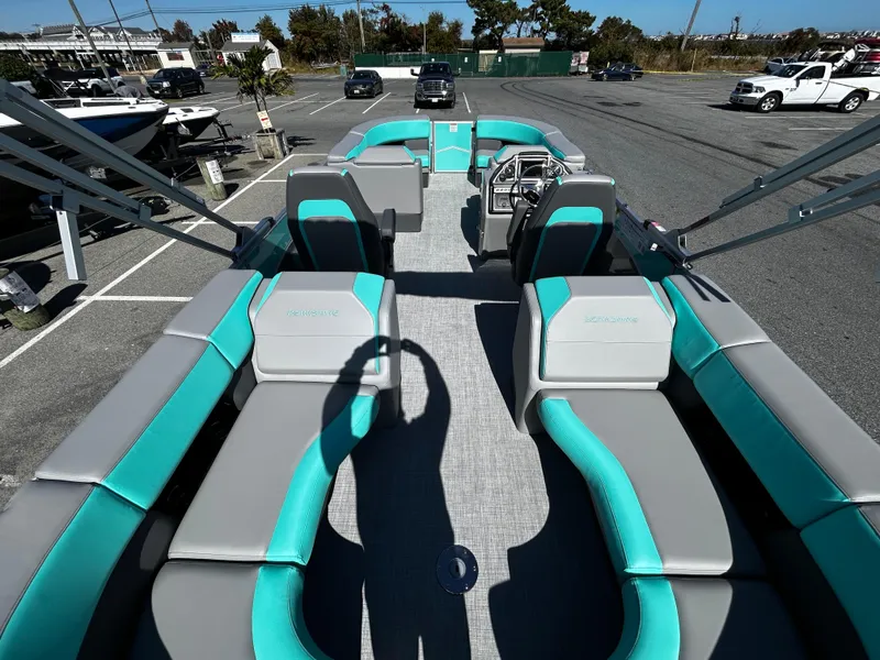 Slide: The Image of 2025 Berkshire 23RFX STS 3.0 pontoon boat with teal and gray seating in a parking lot. - 23