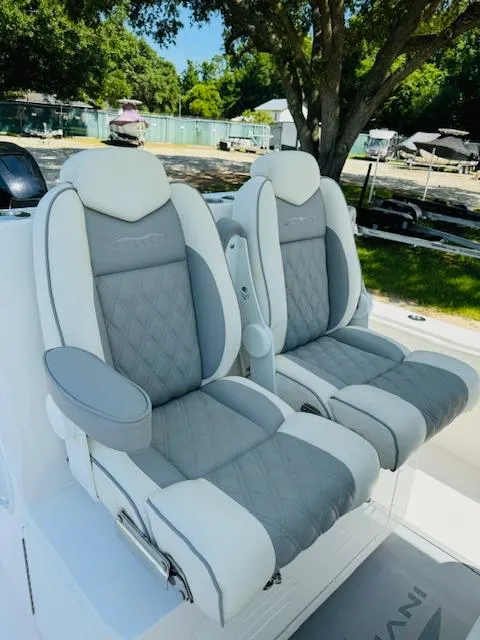 Slide: The Image of 2022 Invincible 36 Open Fisherman boat seats, gray and white leather, outdoor setting. - 14