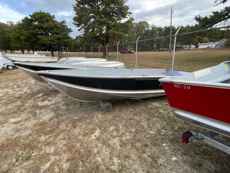 The Image of 2024 Lund WC-14 boats displayed outdoors on grass near a fence. - 0
