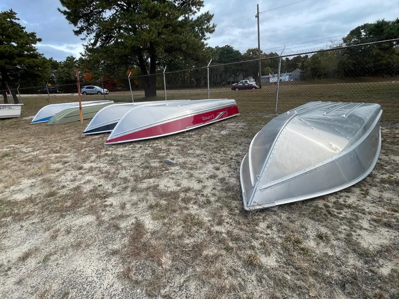 Slide: The Image of Four Lund WC-14 boats, 2024 models, upside down on grass near a fence. - 3