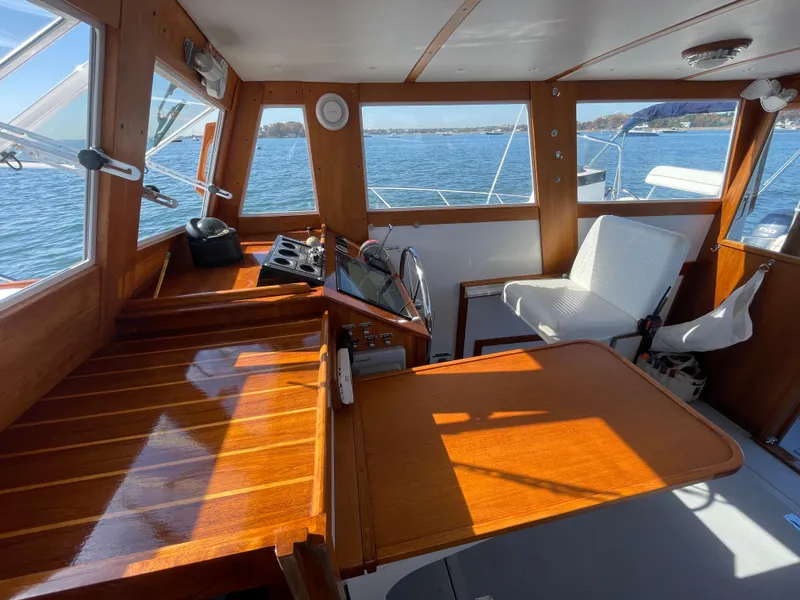Slide: The Image of 1988 Ellis 28 boat interior with wooden helm, white seating, and ocean view. - 19