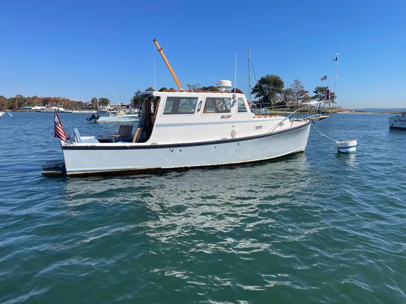 Slide: The Image of 1988 Ellis 28 boat on calm water, clear sky, American flag, coastal background. - 2