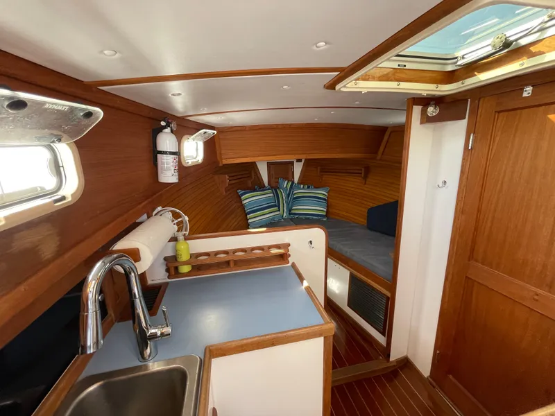Slide: The Image of Interior of 1988 Ellis 28 boat with wooden finish, kitchenette, and cozy seating area. - 25