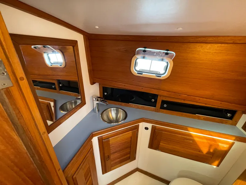 Slide: The Image of 1988 Ellis 28 boat interior with wooden cabinetry, sink, and porthole window. - 26
