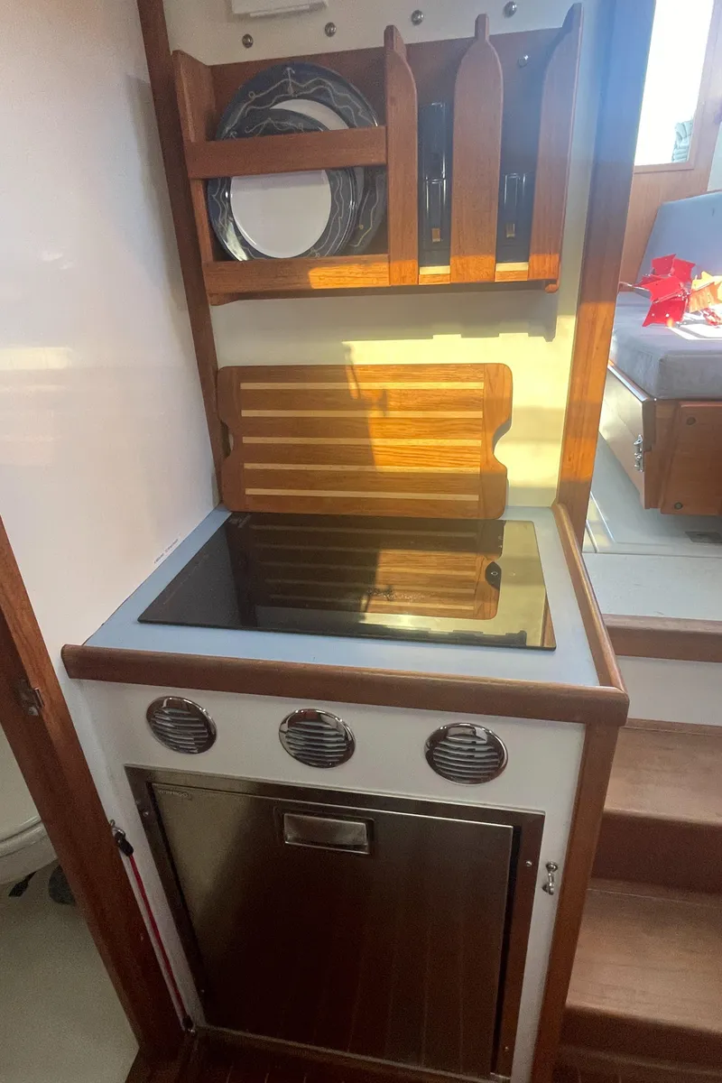 Slide: The Image of Compact kitchen area in a 1988 Ellis 28 boat with stove and storage. - 28