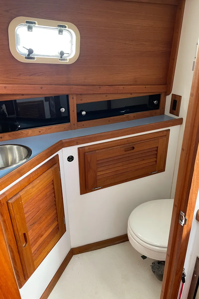 Slide: The Image of 1988 Ellis 28 boat bathroom with wooden cabinets and a porthole window. - 29