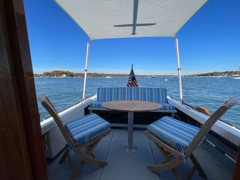 Slide: The Image of Cozy seating on 1988 Ellis 28 boat with striped cushions, lake view, and American flag. - 5