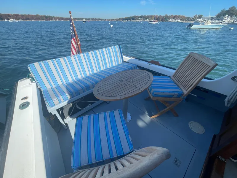 Slide: The Image of 1988 Ellis 28 boat deck with striped seating, wooden table, and scenic water view. - 8