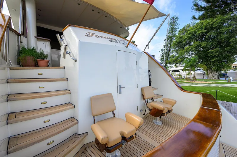 Slide: The Image of 1991 Hatteras 78 CMY yacht deck with seating and stairs, featuring elegant wood finishes. - 12
