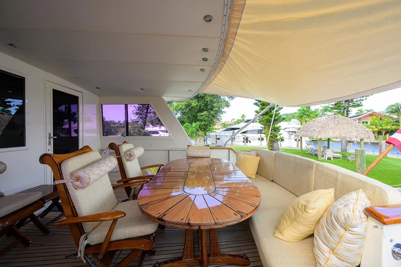 Slide: The Image of Spacious outdoor seating on 1991 Hatteras 78 CMY yacht with wooden table and cushioned chairs. - 18