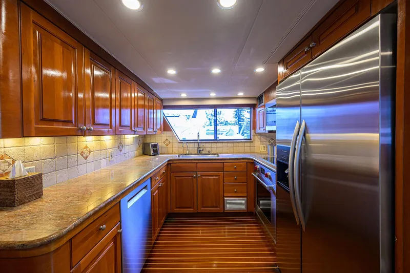 Slide: The Image of Luxurious kitchen interior on 1991 Hatteras 78 CMY yacht with wooden cabinetry and stainless steel appliances. - 27