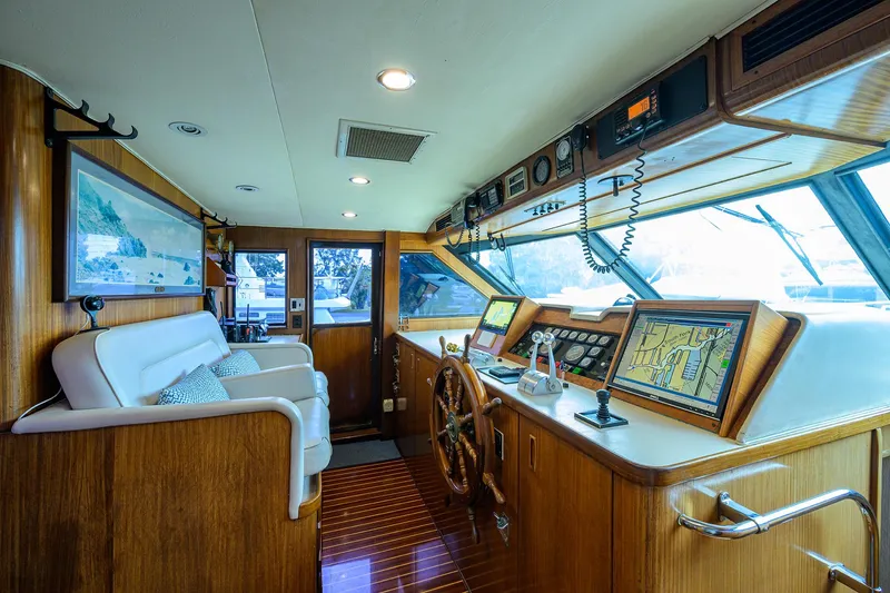 Slide: The Image of Luxurious 1991 Hatteras 78 CMY yacht interior with wooden helm, navigation equipment, and plush seating. - 3