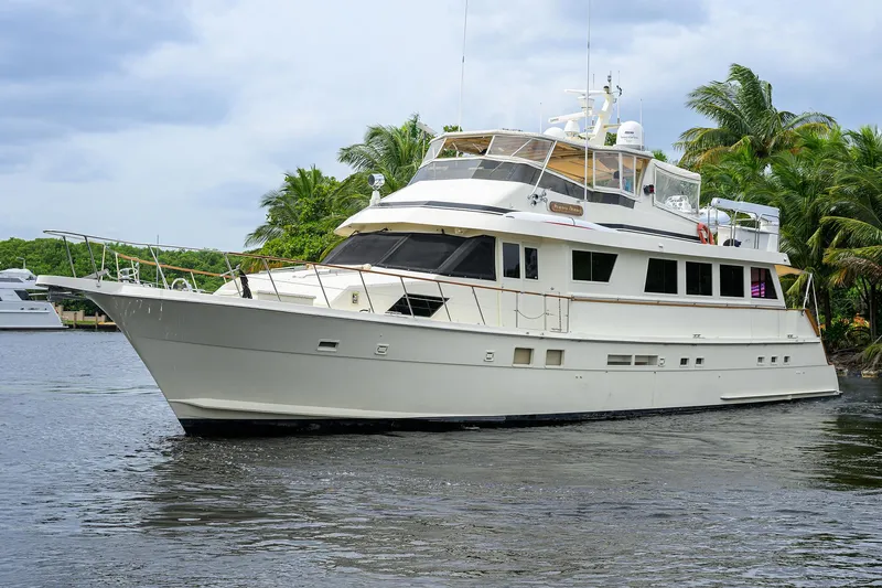 Slide: The Image of Luxury 1991 Hatteras 78 CMY yacht cruising on a serene waterway, surrounded by lush greenery. - 6