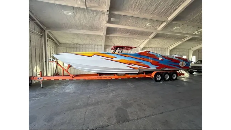 Slide: The Image of 2003 Cigarette 38 Top Gun boat with vibrant graphics on a trailer in a garage. - 1