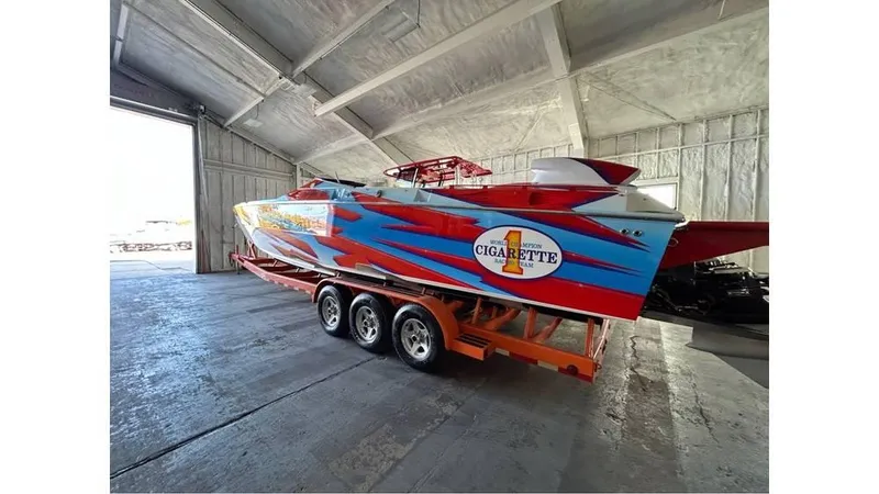 Slide: The Image of 2003 Cigarette 38 Top Gun boat with vibrant graphics in a storage facility. - 2
