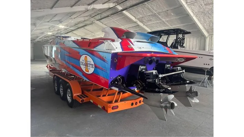 Slide: The Image of 2003 Cigarette 38 Top Gun boat with vibrant graphics on a trailer in a warehouse. - 4