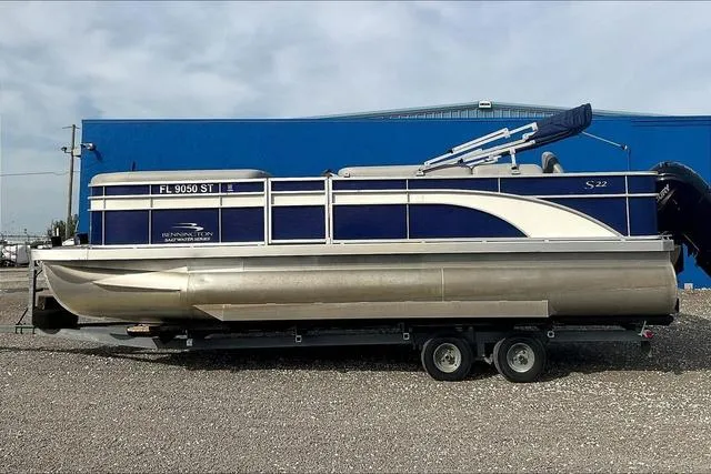 Slide: The Image of 2021 Bennington 22 SL pontoon boat on trailer, blue and silver design, parked outdoors. - 4