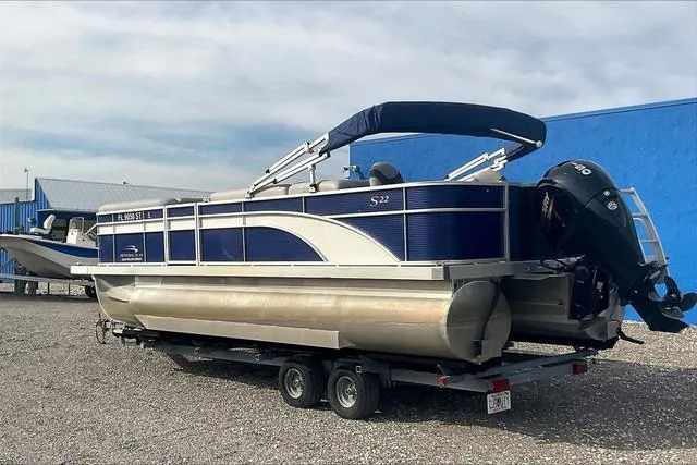 Slide: The Image of 2021 Bennington 22 SL pontoon boat on trailer, blue and silver design, parked outdoors. - 5