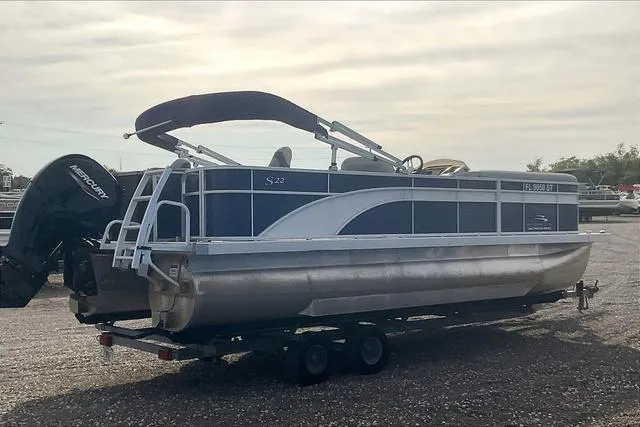 Slide: The Image of 2021 Bennington 22 SL pontoon boat on trailer, featuring a Mercury outboard motor. - 7