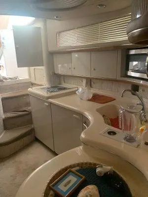 Slide: The Image of Interior of 1996 Sea Ray 450 Sundancer yacht, featuring kitchen area with cabinets and appliances. - 17