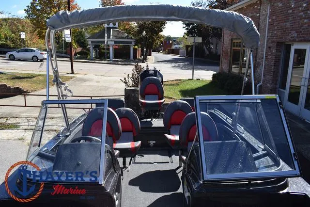 Slide: The Image of 2024 Triton 206 Allure boat with red and black seating, parked outdoors. - 20