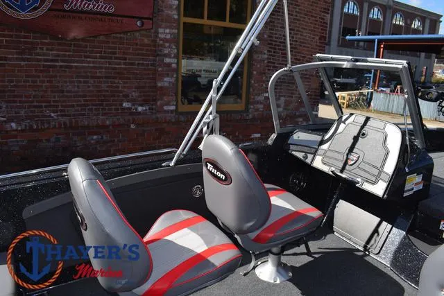 Slide: The Image of 2024 Triton 206 Allure boat interior with red and gray seats, displayed at Thayer's Marine. - 22