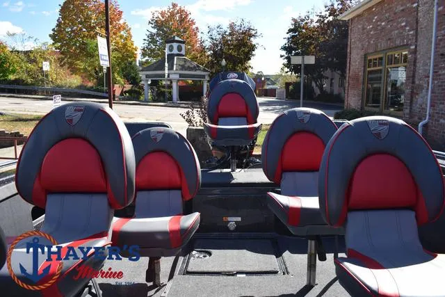 Slide: The Image of 2024 Triton 206 Allure boat seats in a marina setting with autumn trees. - 32
