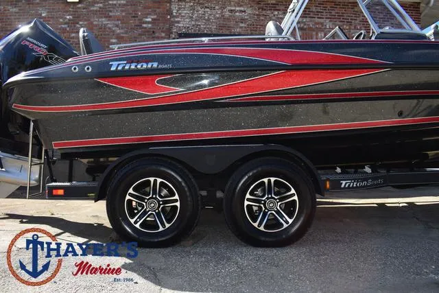 Slide: The Image of 2024 Triton 206 Allure boat with sleek black and red design, displayed at Thayer's Marine. - 5