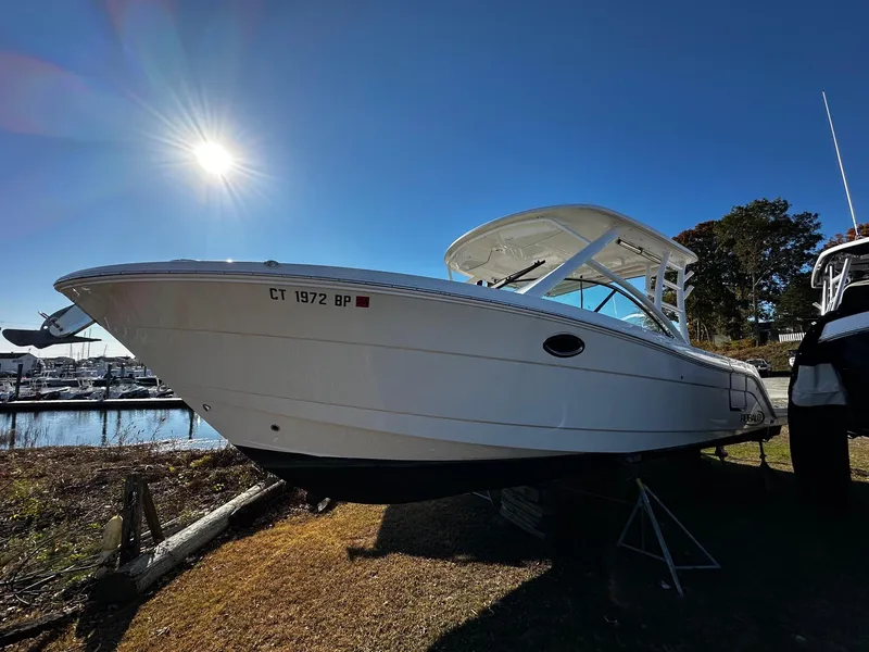 The Image of 2022 Robalo R317 Dual Console boat under bright sun near marina. - 1