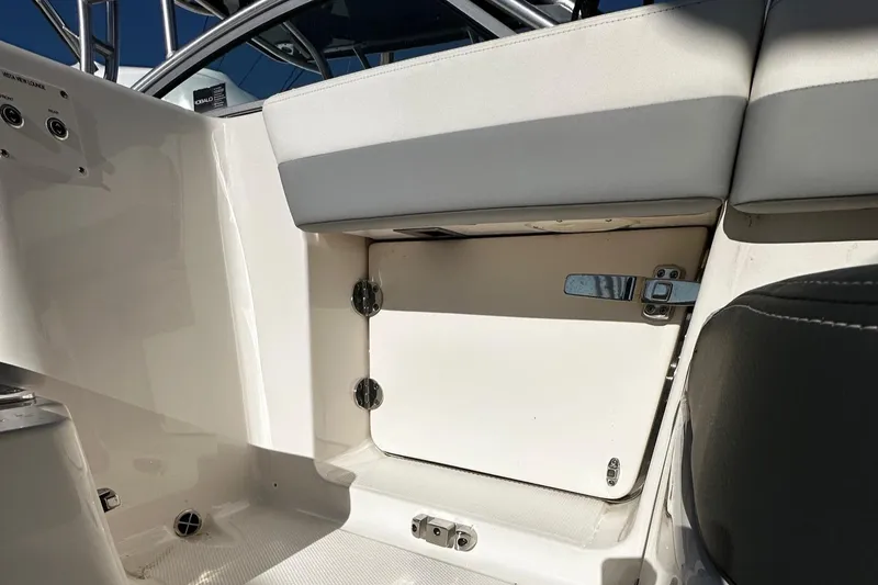 Slide: The Image of 2022 Robalo R317 Dual Console interior storage compartment with white seating and latch. - 15