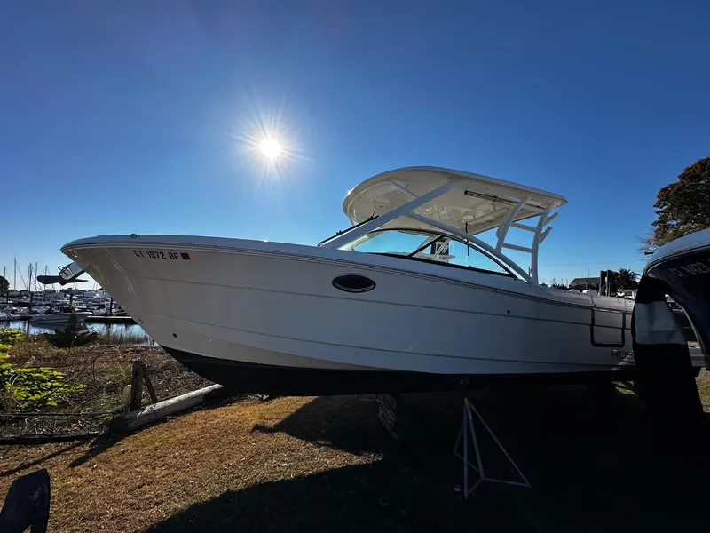 Slide: The Image of 2022 Robalo R317 Dual Console boat under bright sun at marina. - 2