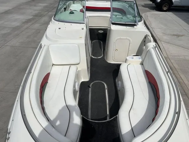 Slide: The Image of 2001 Rinker 243 Siesta DB boat with white and red seating, docked on concrete. - 7