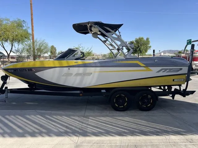 Slide: The Image of 2015 MB SPORTS B52 23 boat on trailer, yellow and gray design, parked outdoors. - 5
