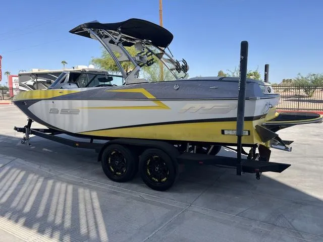 Slide: The Image of 2015 MB SPORTS B52 23 boat on trailer, yellow and gray design, parked outdoors. - 6