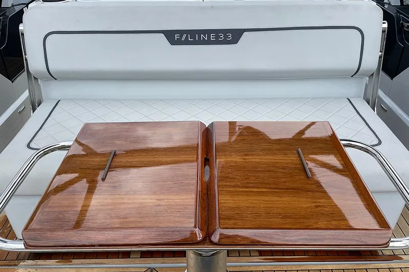 Slide: The Image of Fairline F//Line 33 yacht interior, 2022 model, featuring elegant wooden table and cushioned seating. - 25